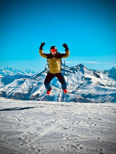 Un skieur saute de joie devant les sommets enneigés